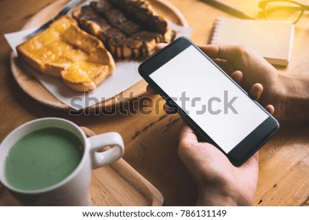 blank white screen or isolated screen of smartphone. woman hand use smart phone
with hot green tea and honey toast in cafe shop in break time.