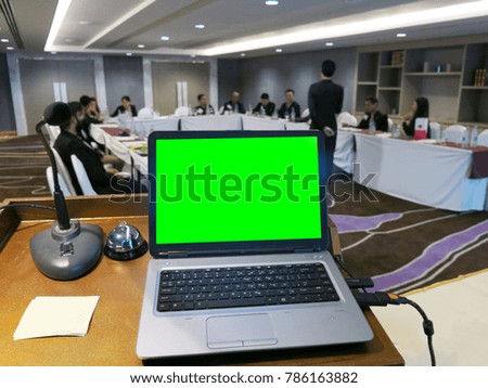 Notebook with green screen on table in meeting room.