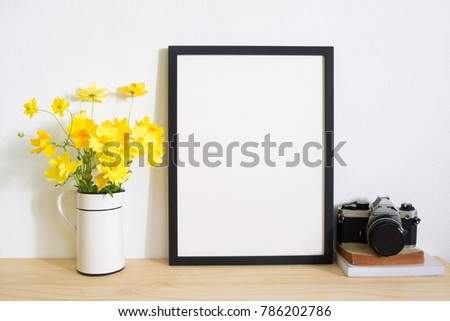 Mock up frame photo with camera and yellow flower in vase on desk