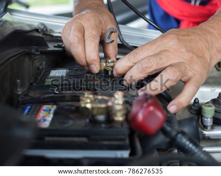 men's hand is polarized brass car battery with wrench Royalty-Free Stock Photo #786276535