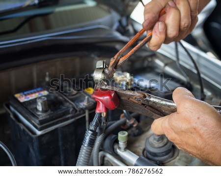 old man's hand fix brass battery terminal on car engine with pliers Royalty-Free Stock Photo #786276562