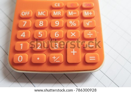 orange calculator on grid white paper