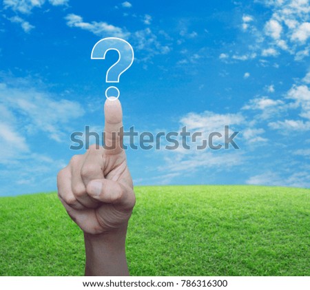 Hand pressing question mark sign icon over green grass field with blue sky, Customer support concept