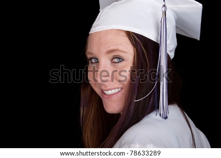 A high-school graduate poses with excitement.  Image is isolated on black.
