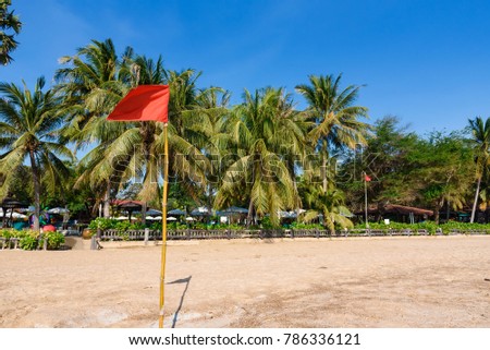Warning sign of a red flag at a beautiful beach with a blue sky at Cha Am beach of Thailand