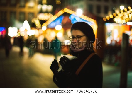 Defocused silhouette of woman eating at the French Christmas Market the traditional bakery tart with defocused view of the market stalls