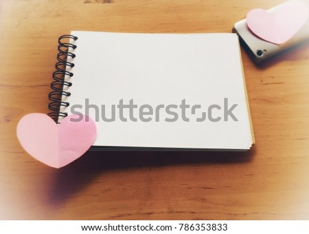 Pink note paper cut into hearts, placed on a white note , wooden floor