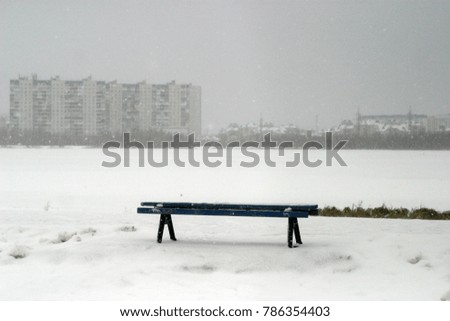 The benches in the park are covered with white snow. Winter holiday background