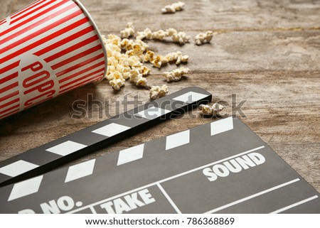 Movie clapper and popcorn on wooden background, closeup