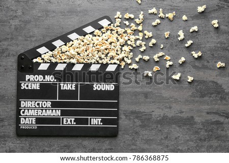 Movie clapper and popcorn on grey background, top view