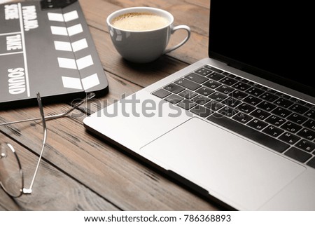 Laptop and movie clapper on wooden table, closeup