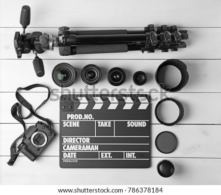 Composition with movie clapper, tripod, camera and different lenses on light background, top view