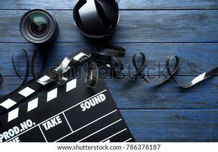 Movie clapper, filmstrip and lenses on wooden background, top view