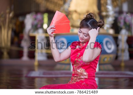 beautiful girl in the Cheongsam red dress up holding red envelop, The symbol of Chinese New Year. festivity and celebration concept
