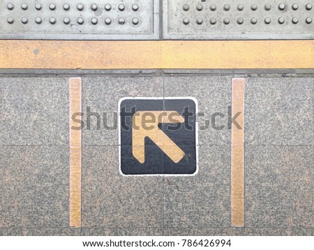 Yellow arrow sign pointing on floor, stand behind the yellow line while waiting for the train in station. Arrow sign show direction for walk in when train arrived.