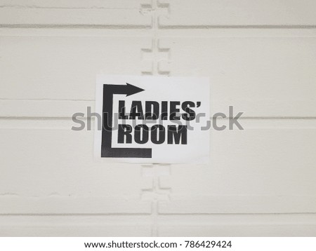 paper sign saying ladies room on white wall