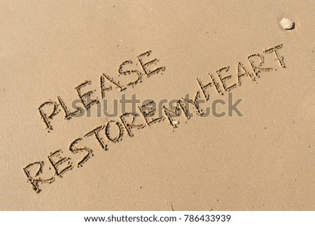 Handwriting  words "PLEASE RESTORE MY HEART." on sand of beach.