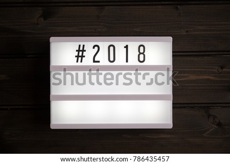 2018 hashtag message in light box, grunge wood table flat lay shot from above