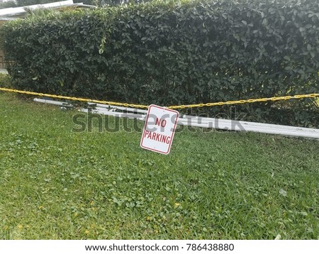 no parking sign with yellow metal chain and green grass