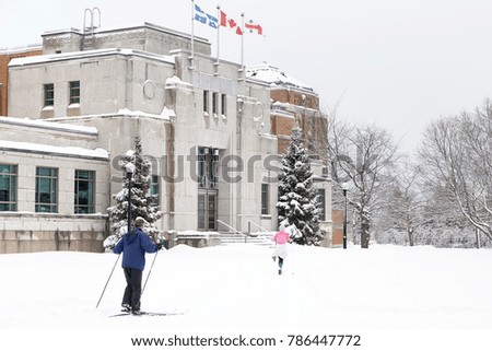 Man and woman cross-country skying in fresh snow with Art Deco Building in the background, Montreal, Quebec, Canada