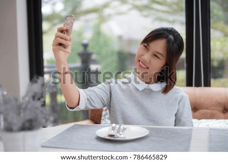 Woman sitting at dining table and selfie using ehr smart phone