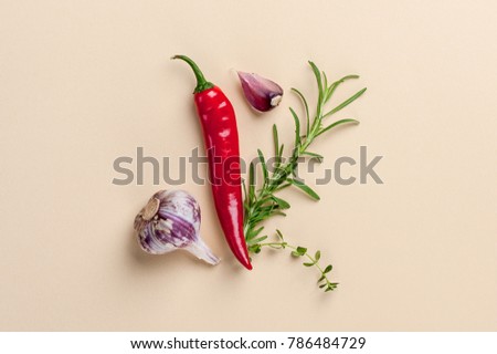 Chili pepper, spicy herbs and garlic - composition on a light beige background.
