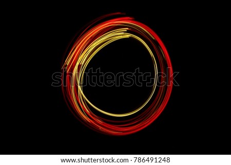 Red and Gold light painting photography, long exposure of fairy lights in a circle outline design, against a black background