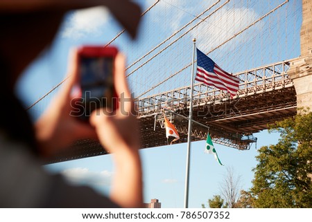 Tourist Taking Photo Of Brooklyn Bridge On Mobile Phone