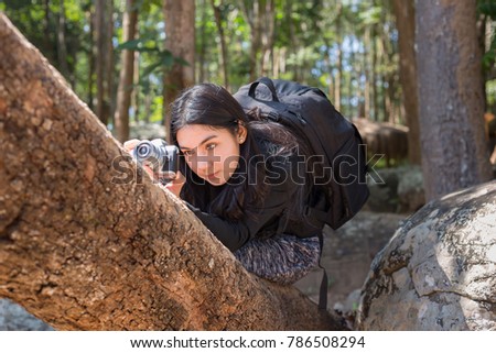 Beautiful asian woman with backpack taking a photo with mirrorless camera.