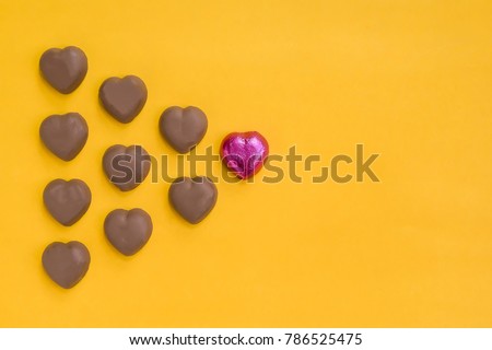 Heart-shaped chocolate brown to red,on yellow background. Royalty-Free Stock Photo #786525475