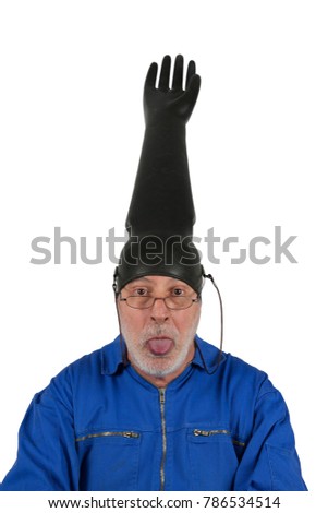An funny old fitter makes nonsense, he has put an inflated rubber glove on his head and sticking out his tongue. He has fun in his job. 