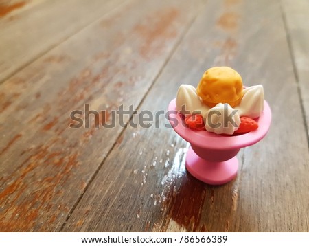 Tiny cute rubber of ice cream sundae on wooden background