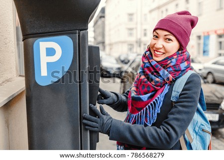 A woman pays for parking her car in an automated terminal of a parkomat