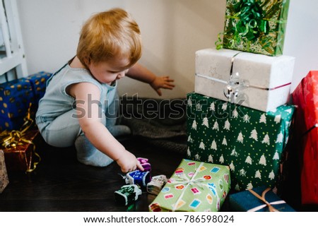 Portrait happy little girl playing with toys, sits on the background gifts. Festive birthday concept. baby on photo. infant. merry Christmas, happy holidays. new year.
