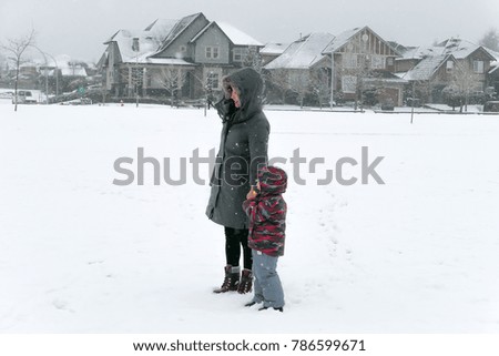 Happy asian pretty young mother and her son play together during winter holidays outside in snow park 
