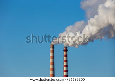 Coal power plant smokestacks emit carbon dioxide pollution by factory under blue sky. Royalty-Free Stock Photo #786695800
