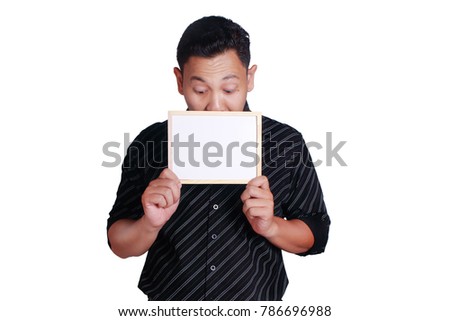 Portrait of young attractive Asian man wearing black shirt, holding and showing small empty copy space whiteboard covering his face, isolated on white