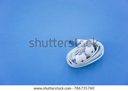 White Spiral Earphones on Blue Background Top View with Copy Space