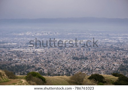Aerial view of residential areas of San Jose, California on a rainy day; the city's financial district in the background; 