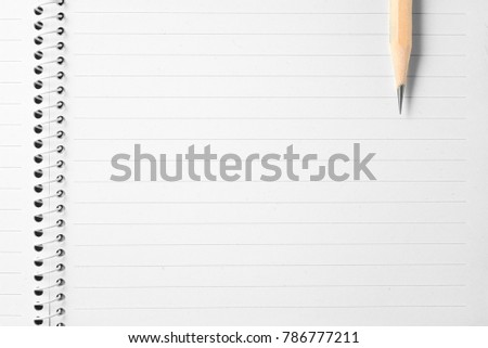 High resolution top view close up photo of wooden pencil put on notebook with copy space in wooden table.Flash light made smooth shadow from wooden pencil and clean look of notebook lined paper.