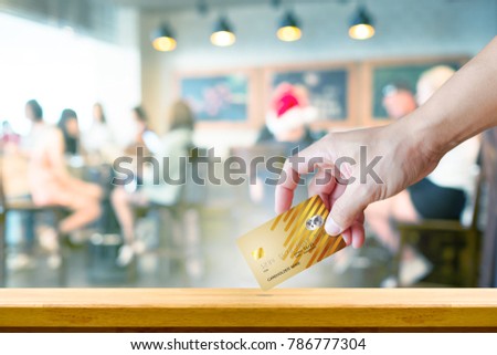 man handle realistic debit or credit card on wood table with coffee shop blur background