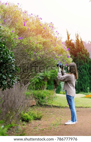 Girl with a digital camera taking pictures outside.