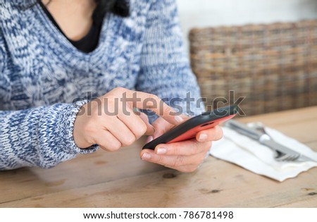Image of young woman texting or chatting on the mobile phone in coffee shop.
