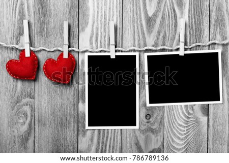 Instant photo frame and love hearts pinned to rope on wooden textured background