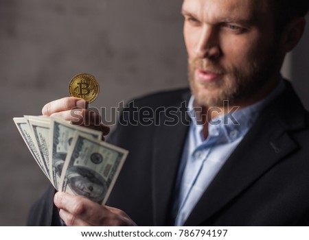 Man holding money and bitcoin. Focus on coin