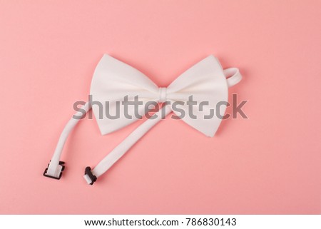 white bow tie with textile band on light pink background