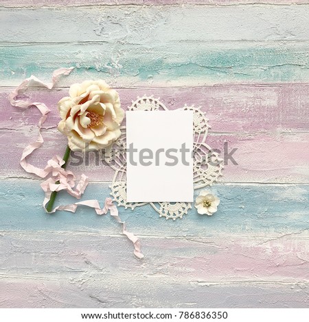 Mockup of the piece of paper with iridescent flower on wooden background