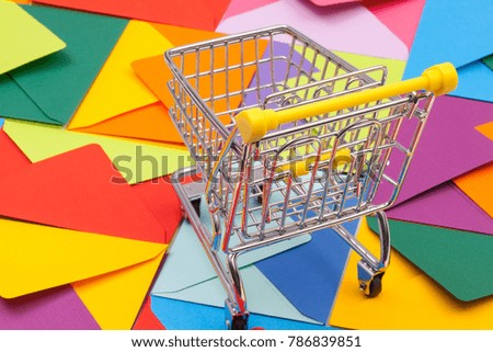 Shopping trolley and different colored envelopes on the table