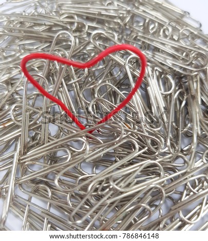 Valentine day concept - soft focus hand made heart-shaped red paper clip on silver paperclip background.
