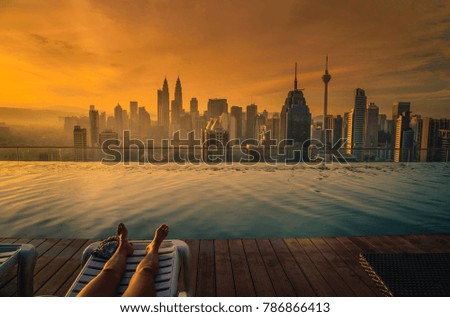 Traveler woman sleep on the sun bed near swimming pool on the roof top of hotel at sunrise in Kuala Lumpur, Malaysia.